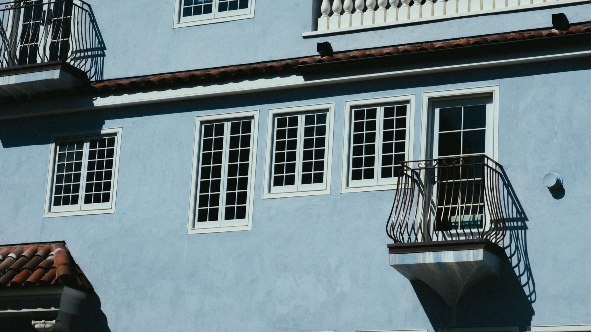 A modern blue building exterior showcasing balconies and windows on a sunny day in Riverside, CA